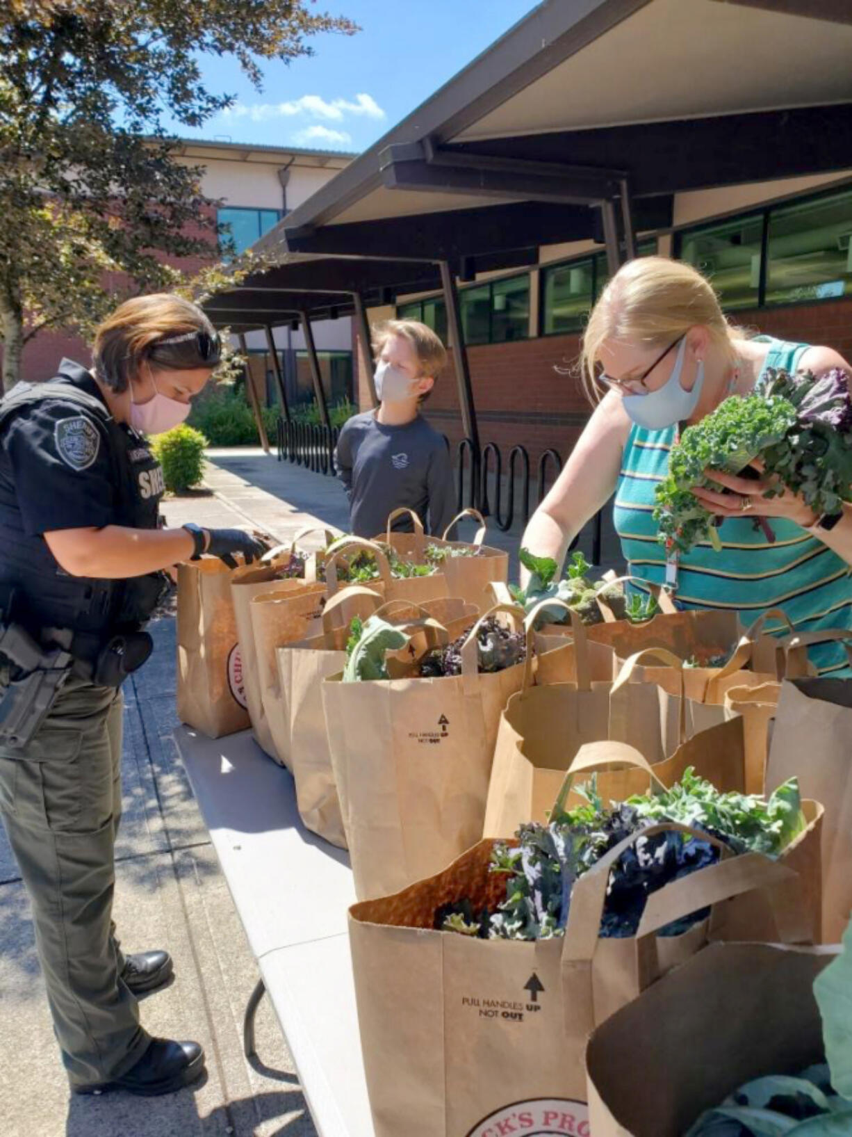 Deputy Amanda Nohrenberg from the Clark County Sheriff's Office, left, volunteers at a fresh food distribution.