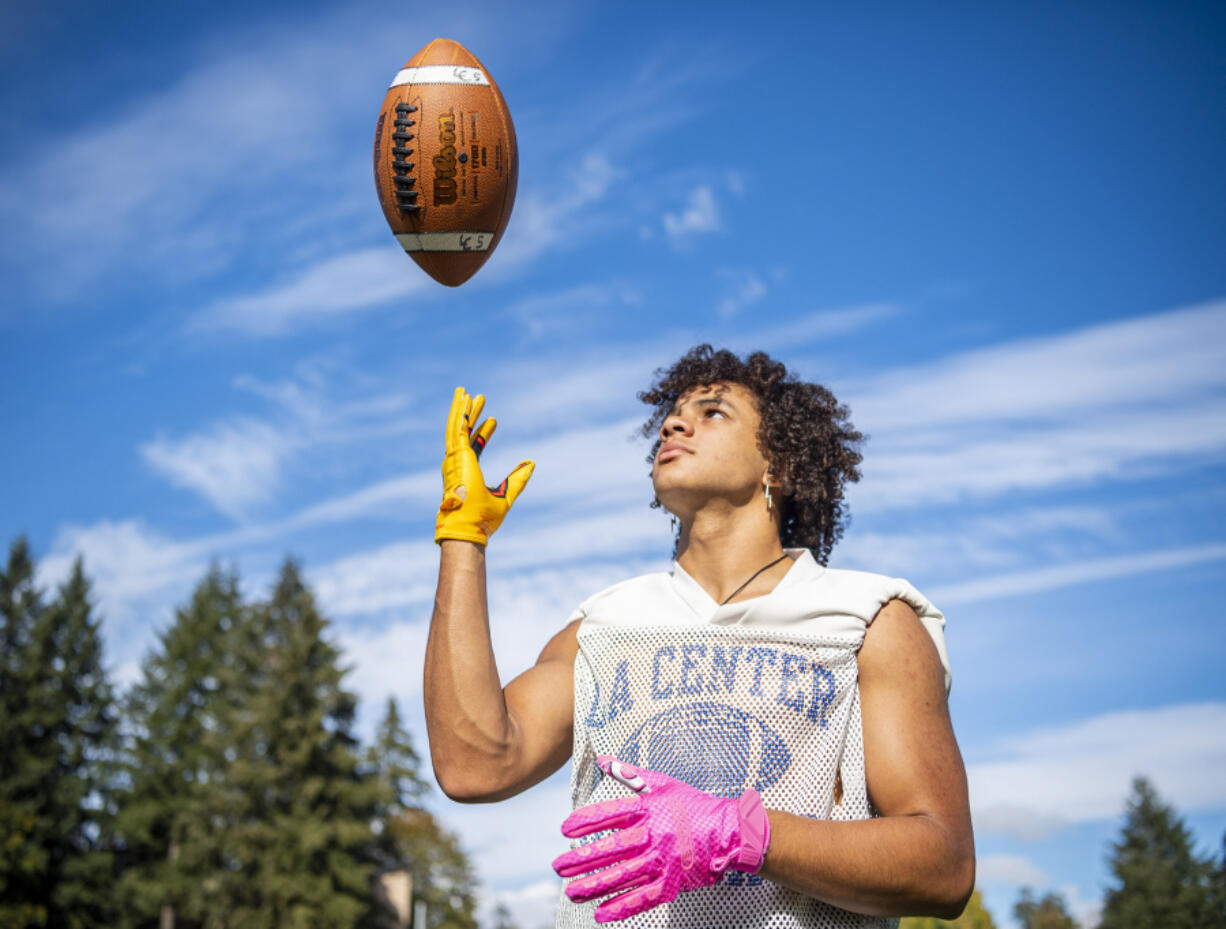 La Center senior receiver Davari Grauer shows off his bright gloves Wednesday, Sept. 28, 2022, at La Center High School. Grauer wears the gloves for his grandfather, who has Alzheimer's. The colorful gloves allow Grauer's grandfather to find his grandson on the field when he forgets what number he wears.