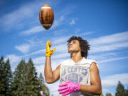 La Center senior receiver Davari Grauer shows off his bright gloves Wednesday, Sept. 28, 2022, at La Center High School. Grauer wears the gloves for his grandfather, who has Alzheimer's. The colorful gloves allow Grauer's grandfather to find his grandson on the field when he forgets what number he wears.