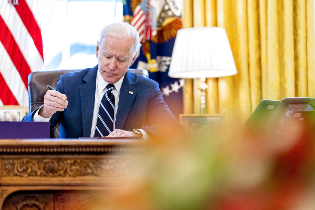 FILE - President Joe Biden signs the American Rescue Plan, a coronavirus relief package, in the Oval Office of the White House, March 11, 2021, in Washington. It's been one year since President Joe Biden signed into law the American Rescue Plan. The $1.9 trillion package of relief measures was designed to fight the coronavirus pandemic and help the economy rebound.