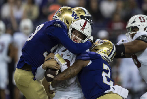 Washington's Zion Tupuola-Fetui, left, and Cam Bright, right, sack Stanford quarterback Tanner McKee during the first half of an NCAA college football game Saturday, Sept. 24, 2022, in Seattle.
