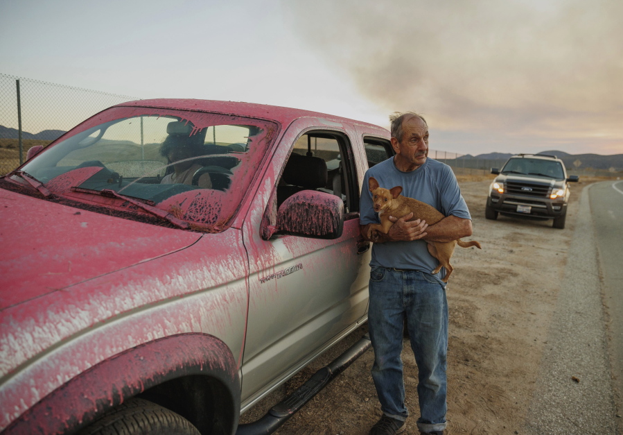 Rick Fitzpatrick holds a dog after evacuating from the Fairview Fire Monday, Sept. 5, 2022, near Hemet, Calif.