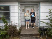 Misty Castillo, left, and her husband Arcadio stand in front of their home, holding the urn containing the ashes of their son Arcadio Castillo III, who was shot in 2021 by Salem police, as their granddaughter Nala, age 2, looks out the window in Salem, Ore., Thursday, Aug. 18, 2022. Misty called 911 and asked for the police, saying her son was mentally ill, was assaulting her and her husband and had a knife. Less than five minutes later, a police officer burst into the house and shot him.