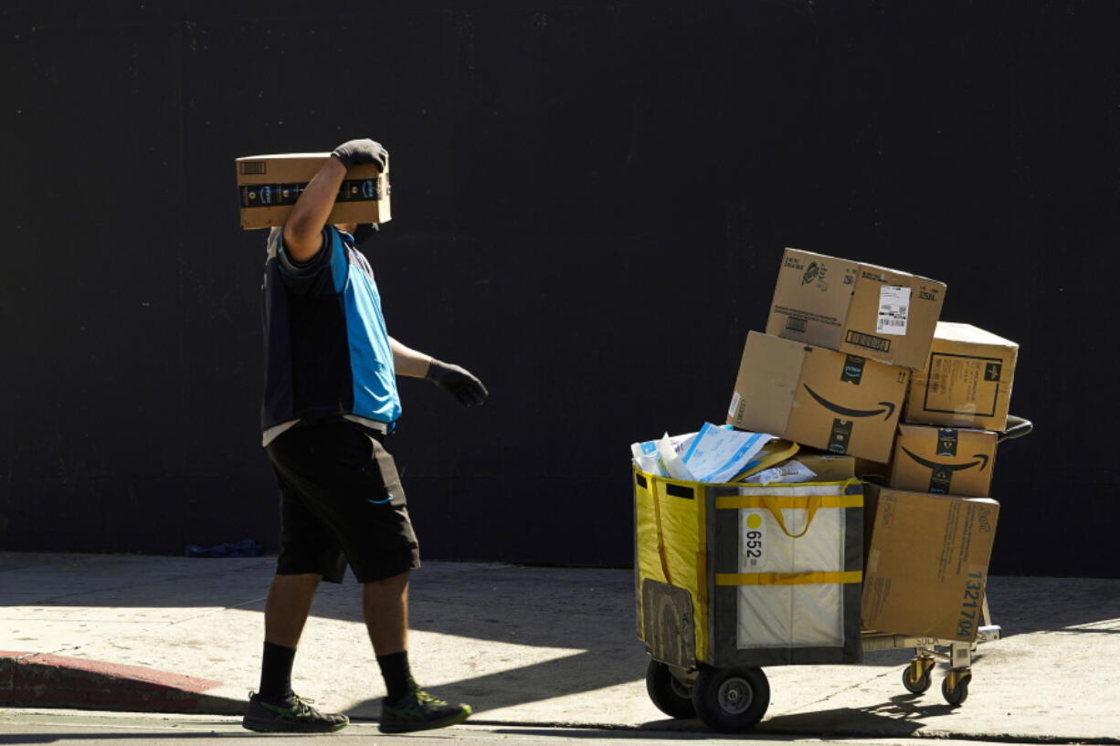 FILE - An Amazon worker delivers boxes in Los Angeles on Oct. 1, 2020. Amazon said Wednesday, Sept. 28, 2022, that it is raising its average starting pay for frontline workers from $18 to $19 a hour, a boost that could help it attract more employees in a tight labor market as the holiday season approaches.