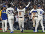 Seattle Mariners' Eugenio Suarez, center, celebrates with Luis Castillo, left, Taylor Trammell (20), Julio Rodriguez, second from right, and third base coach Manny Acta, right, after hitting a walkoff solo home run after a baseball game against the Atlanta Braves, Sunday, Sept. 11, 2022, in Seattle.