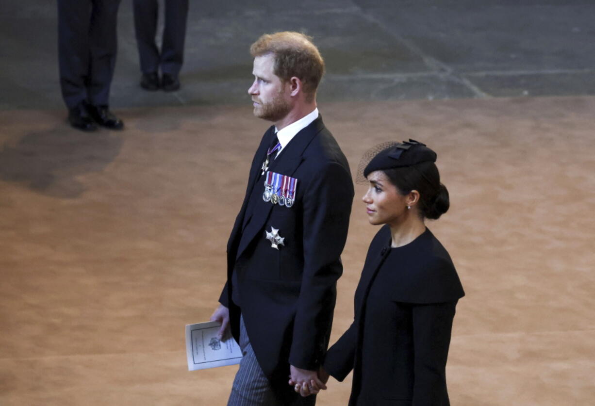 Britain's Prince Harry and Meghan, Duchess of Sussex, walk inside Westminster Hall in London, Wednesday. The couple's exit from royal duties caused a scandal.