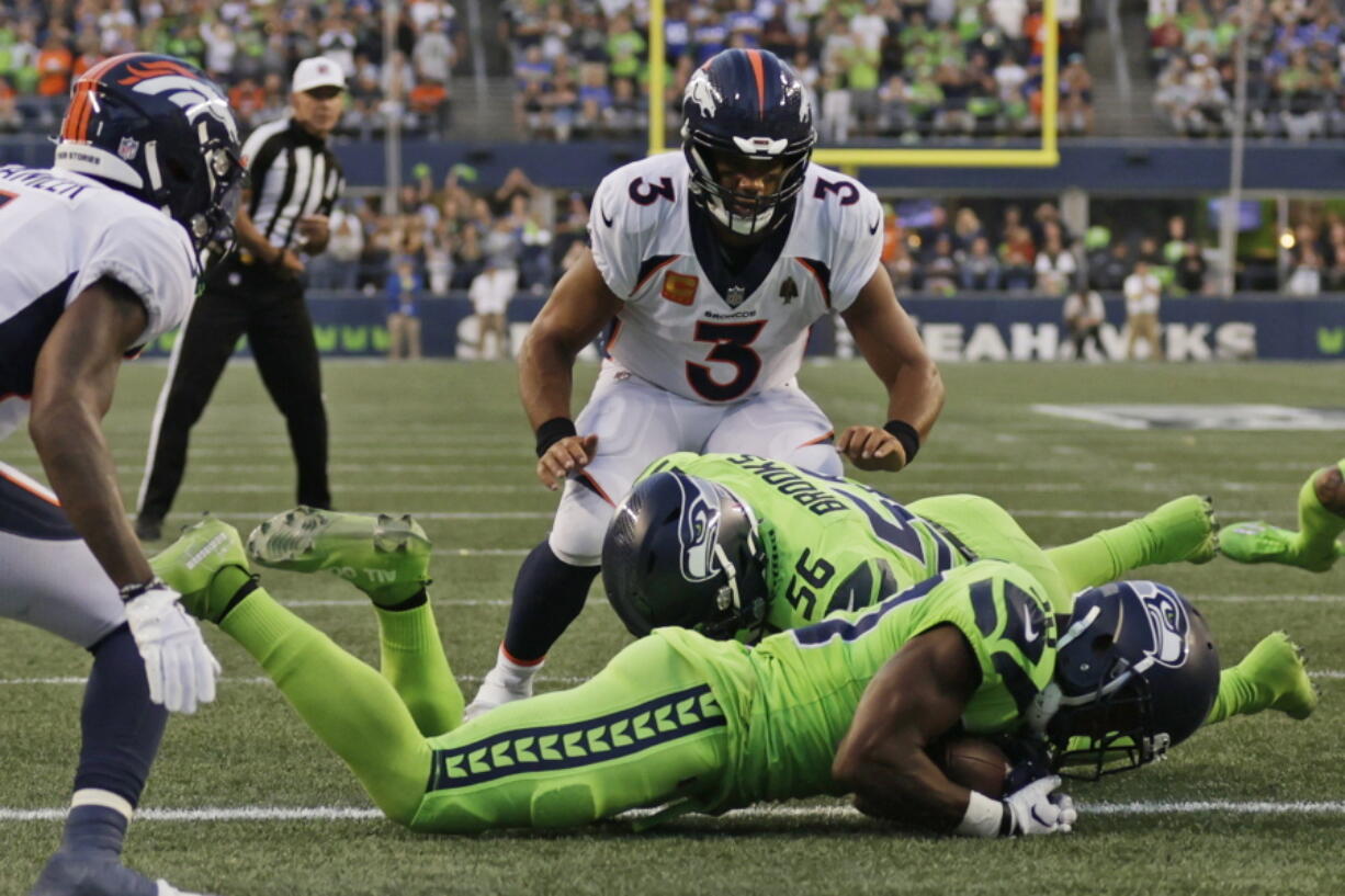 Denver Broncos quarterback Russell Wilson (3) watches as Seattle Seahawks cornerback Mike Jackson, front, recovered the football after it was fumbled by Broncos running back Javonte Williams during the second half of an NFL football game, Monday, Sept. 12, 2022, in Seattle.