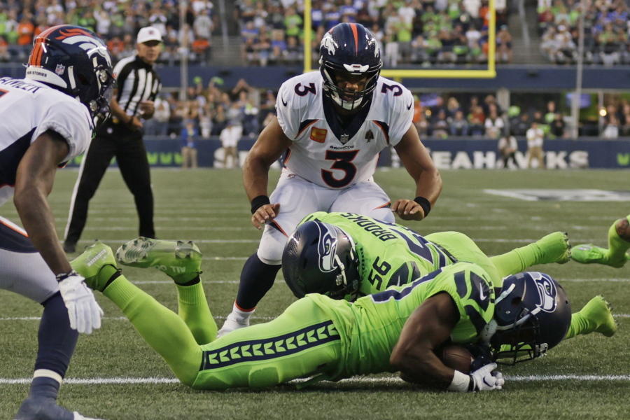 Denver Broncos quarterback Russell Wilson (3) watches as Seattle Seahawks cornerback Mike Jackson, front, recovered the football after it was fumbled by Broncos running back Javonte Williams during the second half of an NFL football game, Monday, Sept. 12, 2022, in Seattle.