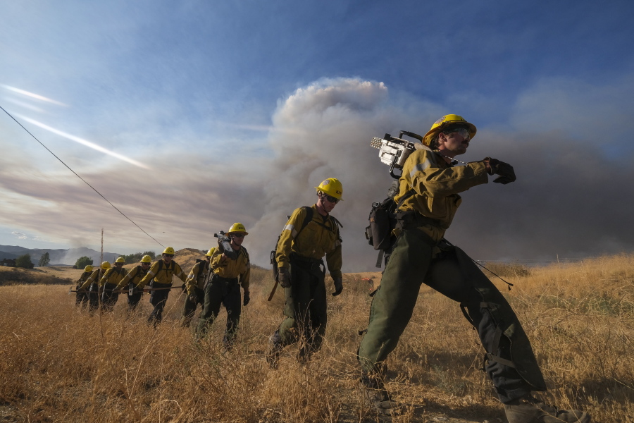 Firefighters walk in a line during a wildfire in Castaic, Calif. on Wednesday, Aug. 31, 2022. (AP Photo/Ringo H.W.