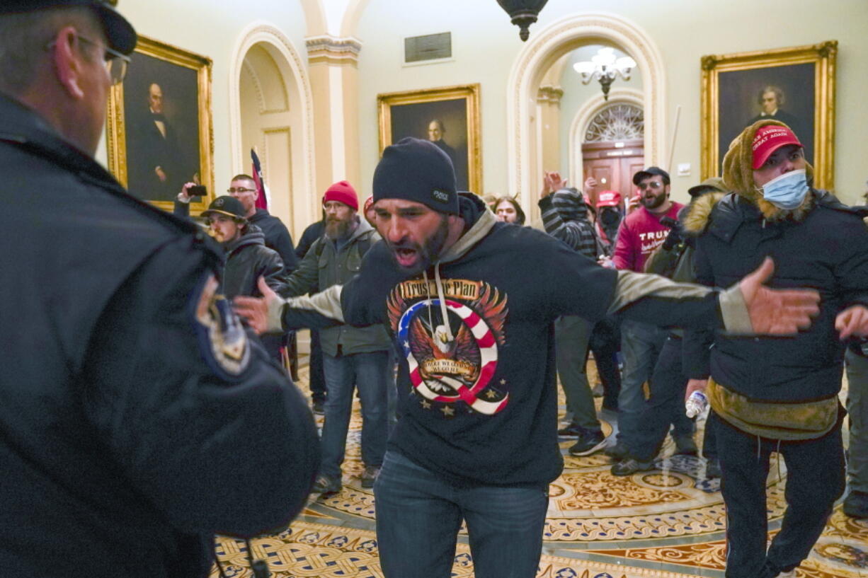 FILE - Trump supporters, including Doug Jensen, center, confront U.S. Capitol Police in the hallway outside of the Senate chamber, Jan. 6, 2021, at the Capitol in Washington.  A trial is set to open for Jensen, who ran after a police officer retreating up a flight of stairs during a mob's attack on the U.S. Capitol, a harrowing encounter captured on video. Jensen, who wore a shirt promoting the QAnon conspiracy theory, told the FBI that he wanted to be a "poster boy" for the events that unfolded on Jan. 6, 2021.