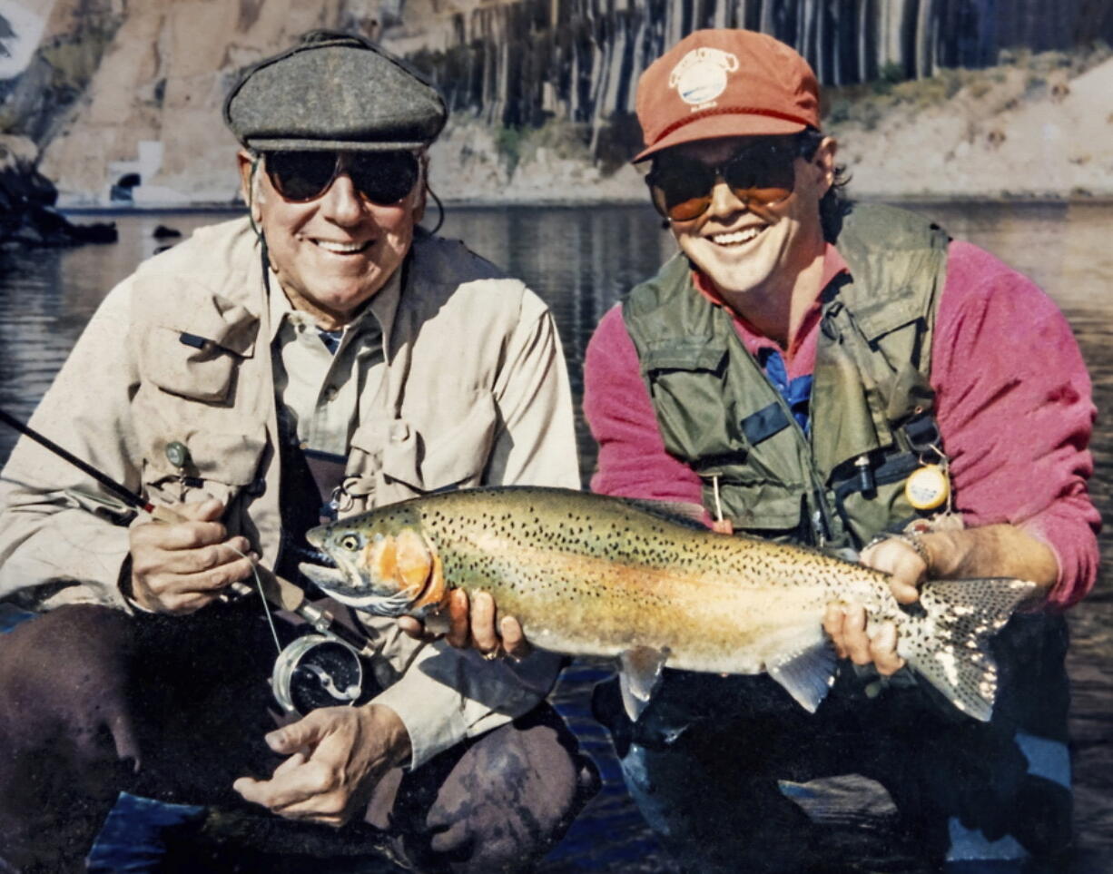 In this photo provided by Terry Gunn, Lehman Beardsley, left, and Gunn, who guides fishing trips, pose with a rainbow trout at Lees Ferry near Marble Canyon, Ariz., Nov 7, 1987. As Lake Powell reservoir just upstream declines, it sends warmer water with less oxygen into the river below the dam. Should that water reach 73 degrees, Gunn said his family's guide service may start calling off afternoon trips.