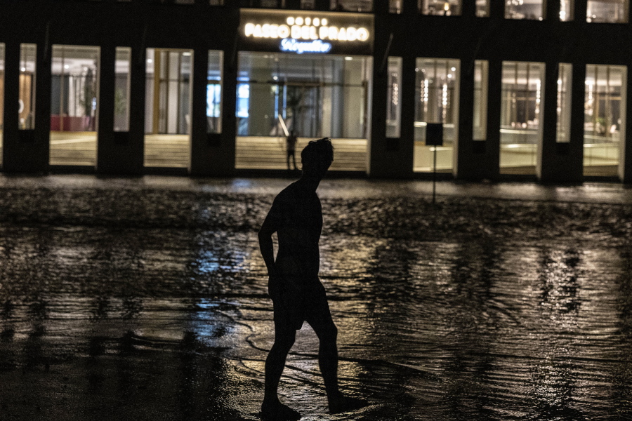 A man walks through a flooded street in front of a hotel powered by an oil generator during a blackout in Havana, Cuba, Wednesday, Sept. 28, 2022. Cuba remained in the dark early Wednesday after Hurricane Ian knocked out its power grid and devastated some of the country's most important tobacco farms when it hit the island's western tip as a major storm.