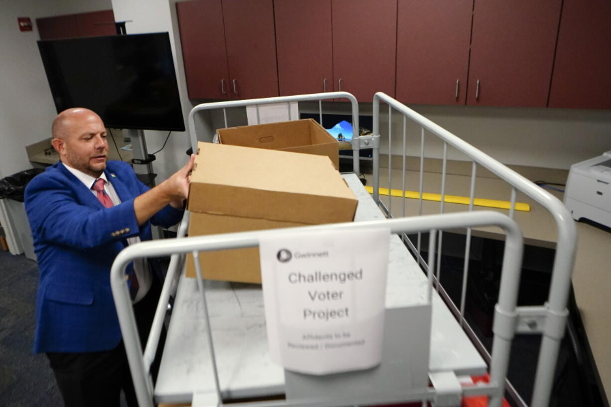 Gwinnett County elections supervisor Zach Manifold looks over boxes of voter challenges on Thursday, Sept. 15, 2022, in Lawrenceville, Ga. Manifold estimated his office has a month to log and research the challenges, before mail ballots go out for the November elections. 
