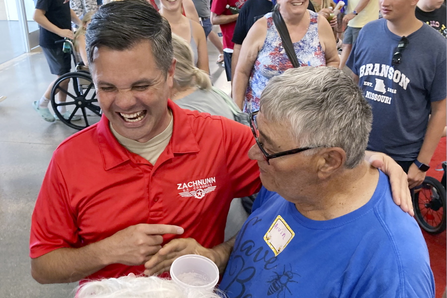 Iowa Republican candidate for Congress Zach Nunn, left, laughs while talking with Arvin Foell of Kelley, Iowa, during an appearance at the Iowa State Fair, in Des Moines, Iowa, August 12, 2022. Nunn is among more than a dozen strict abortion opponents running in competitive House, Senate and governor races working to soften his profile in light of increased enthusiasm among Democratic voters since the June U.S. Supreme Court decision reversing a federal right to abortion.