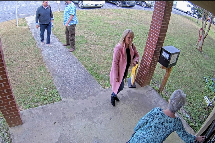 CORRECTS DATE TO JAN. 7, 2021. NOT JAN. 19 In this Jan. 7, 2021 image taken from Coffee County, Ga., security video, Cathy Latham, bottom, who was the chair of the Coffee County Republican Party at the time, greets a team of computer experts from data solutions company SullivanStrickler at the county elections office in Douglas, Ga. Records show that the team traveled to the rural south Georgia county to copy software and data from elections equipment. The Georgia secretary of state's office has said the visit was an "alleged unauthorized access" of election equipment.
