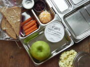 A vegetarian boxed school lunch with carrot sticks and fruit.
