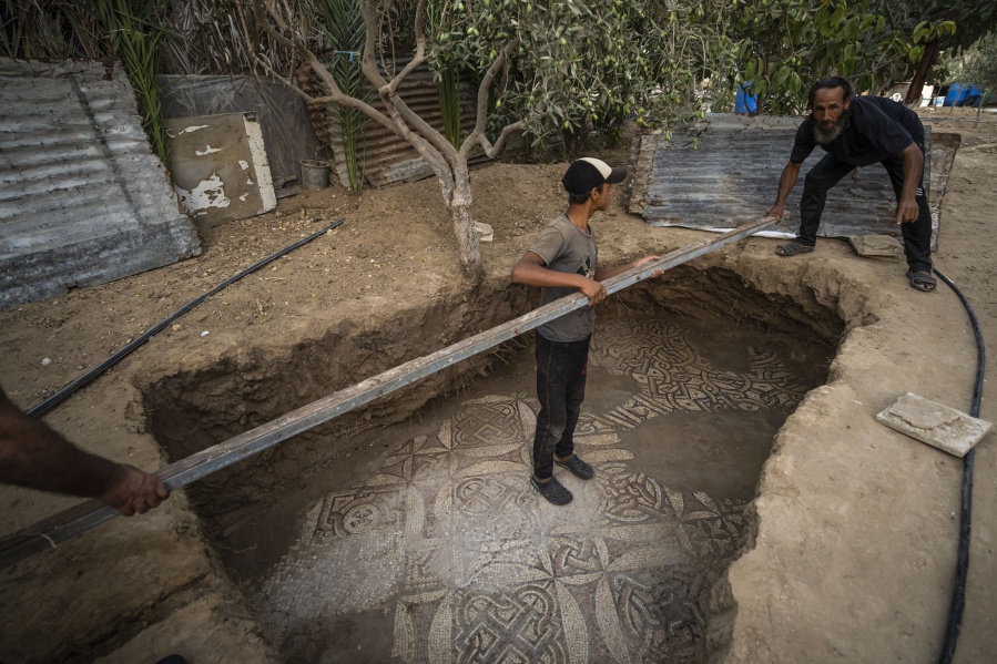 Palestinians clean around a Byzantine-era mosaic floor that was uncovered recently by a farmer in Bureij in central Gaza Strip, Sept. 5, 2022. The man says he stumbled upon it while planting an olive tree last spring and quietly excavated it over several months with his son. Experts say the discovery of the mosaic -- which includes 17 well-preserved images of animals and birds -- is one of Gaza's greatest archaeological treasures. They say it's drawing attention to the need to protect Gaza's antiquities, which are threatened by a lack of resources and the constant threat of fighting with Israel.