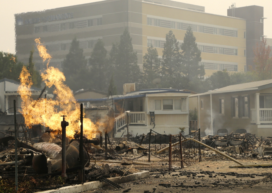 FILE - With Kaiser Permanente's Santa Rosa Medical Center in the background, a flame from an open gas valve burns at the Journey's End mobile home park on Oct. 9, 2017, in Santa Rosa, Calif. Dr. Suzy Fitzgerald helped with the evacuation of 122 patients from Kaiser Permanente's Santa Rosa Medical Center nearly five years ago, as the blaze gobbled up homes and buildings across Northern California. The hospital, which had filled with smoke, closed for 17 days.