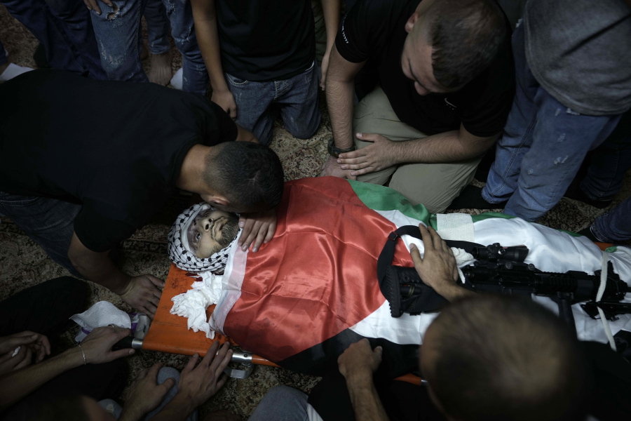 Mourners surround the Palestiian flag-draped body of Muhammad Alawneh, killed during an Israeli military raid in the occupied West Bank town of Jenin, Wednesday, Sept. 28, 2022. At least four Palestinians were killed and dozens of others wounded, the Palestinian Health Ministry reported, the latest in a series of deadly Israeli operations in the occupied territory.