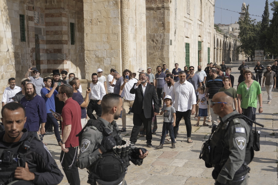 Israeli police officers escort lawmaker Itamar Ben-Gvir, center, and a group of Jewish men as they visit the Temple Mount, known to Muslims as the Noble Sanctuary, on the Al-Aqsa Mosque compound in the Old City of Jerusalem, during the annual mourning ritual of Tisha B'Av (the ninth of Av) a day of fasting and a memorial day, commemorating the destruction of ancient Jerusalem temples, Sunday, Aug. 7, 2022. Ben-Gvir, an ultranationalist lawmaker who was once relegated to the margins of Israeli politics, is surging in the polls ahead of November's parliamentary elections.