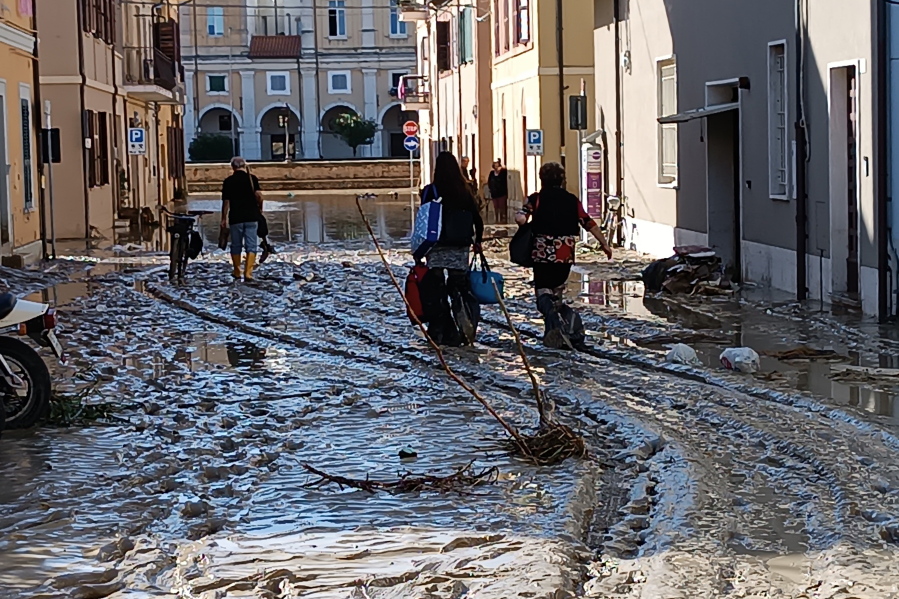 People walk on mud and debriS  in Senigallia, Italy, Friday Sept. 16, 2022. Floodwaters triggered by heavy rainfall swept through several towns in a hilly region of central-east Italy early Friday, leaving 10 people dead and several missing, state radio said. Dozens of survivors scrambled onto rooftops or up trees to await rescue.
