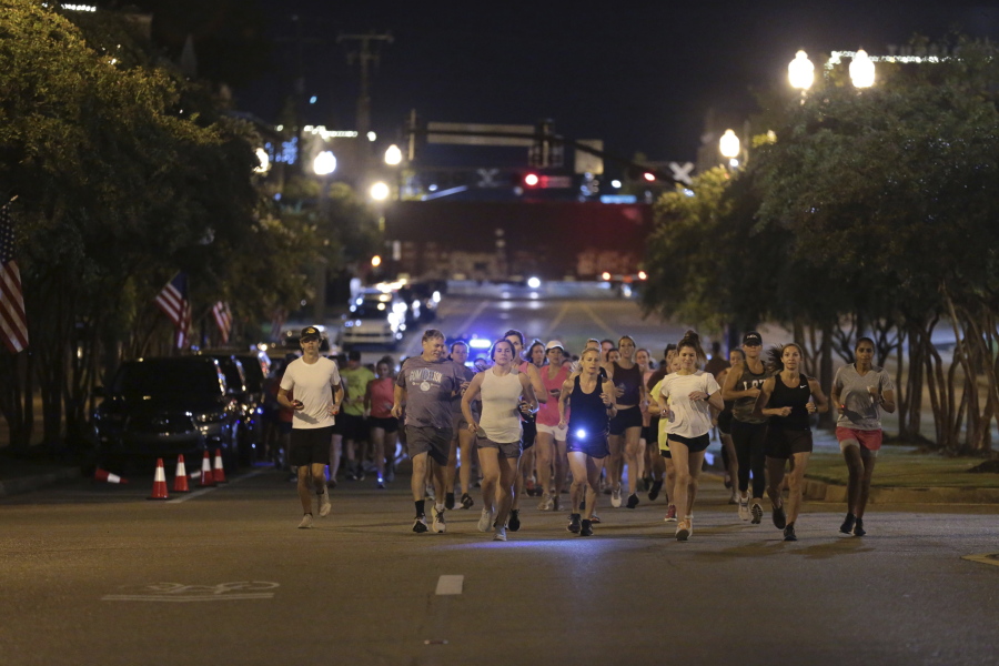 Runners make their way down Main Street in Tupelo, Miss. as they hold their "Liza's Lights" run early Friday morning, Spet. 9, 2022, in Tupelo Miss., to remember Eliza Fletcher, who was abducted and murdered while she was running in the early morning hours in Memphis, Tenn.