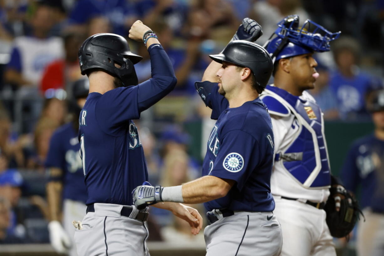 Seattle Mariners' Jesse Winker, left, congratulates Cal Raleigh at home plate after Raleigh's two-run home run against the Kansas City Royals during the sixth inning of a baseball game in Kansas City, Mo., Saturday, Sept. 24, 2022. (AP Photo/Colin E.