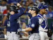 Seattle Mariners' Jesse Winker, left, congratulates Cal Raleigh at home plate after Raleigh's two-run home run against the Kansas City Royals during the sixth inning of a baseball game in Kansas City, Mo., Saturday, Sept. 24, 2022. (AP Photo/Colin E.