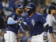 Kansas City Royals' Edward Olivares (14) congratulates Salvador Perez, right, after Perez scored from second off a Vinnie Pasquantino single during the seventh inning of a baseball game against the Seattle Mariners in Kansas City, Mo., Friday, Sept. 23, 2022. (AP Photo/Colin E.