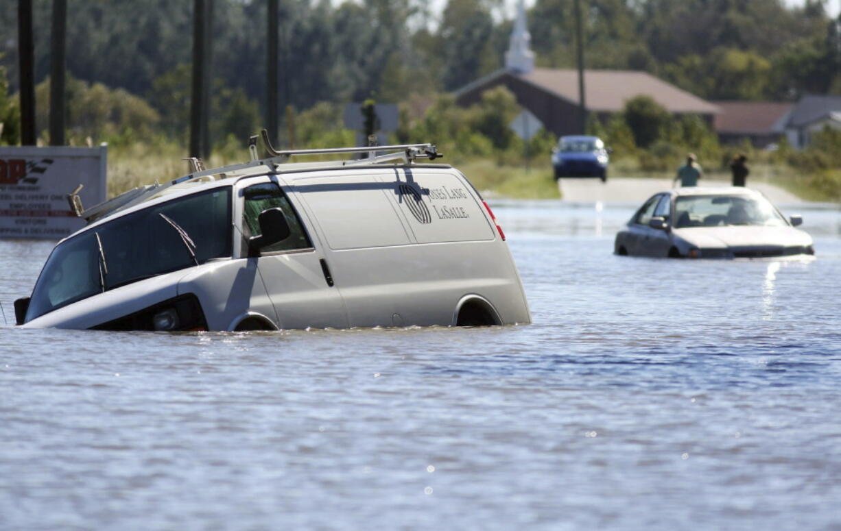 FILE - Several abandoned vehicles sit in flood waters caused by Hurricane Matthew at the intersection of John and Benton streets in Goldsboro, N.C., Monday, Oct. 10, 2016. Nearly six years after extreme rainfall and flooding from Hurricane Matthew damaged many North Carolina homes, some homeowners are still left waiting on repairs. A new bipartisan General Assembly committee tasked with investigating the delays holds its first meeting Wednesday, Sept. 14, 2022, on the four-year anniversary of when Hurricane Florence made landfall in North Carolina.