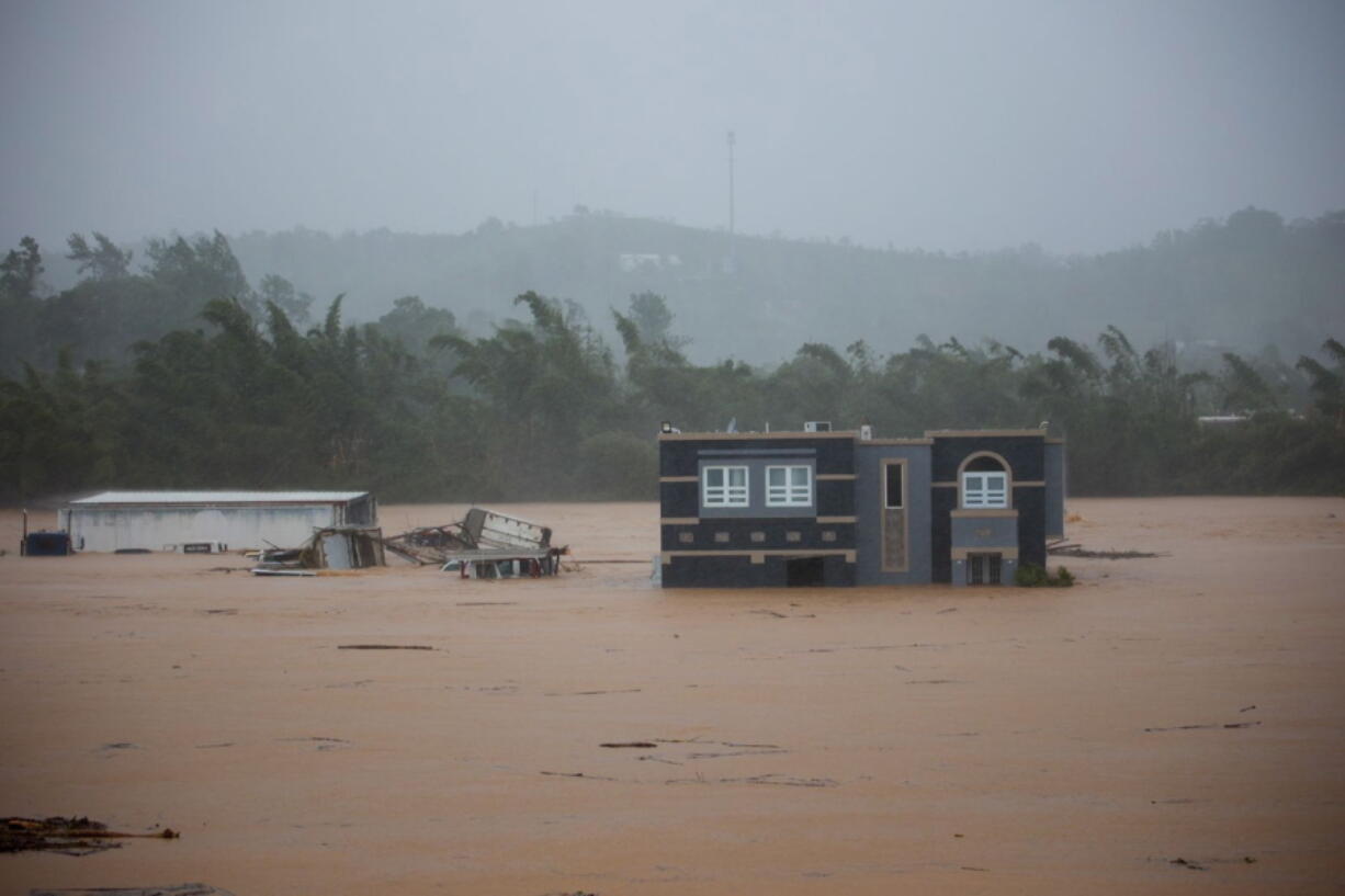 A home is submerged in floodwaters caused by Hurricane Fiona in Cayey, Puerto Rico, Sunday, Sept. 18, 2022.  According to authorities three people were inside the home and were reported to have been rescued.