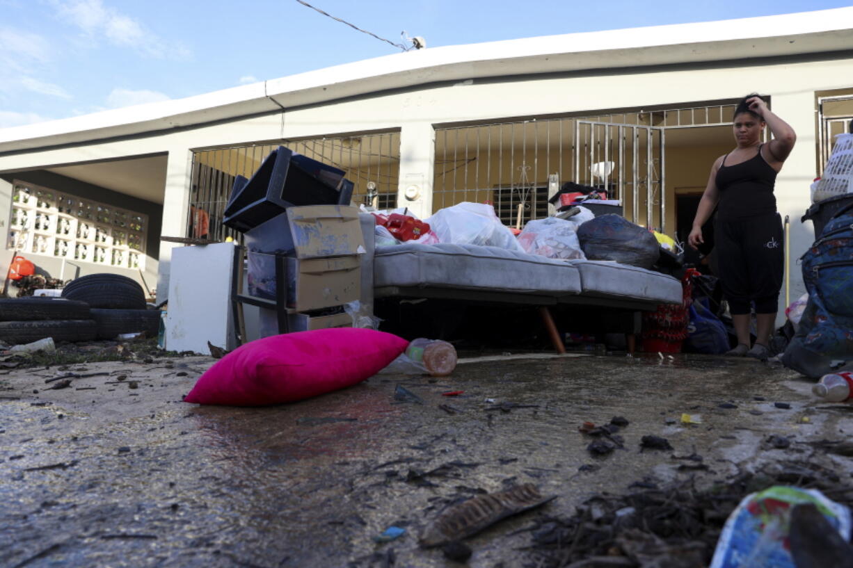 A woman looks at her water-damaged belongings after flooding caused by Hurricane Fiona tore through her home in Toa Baja, Puerto Rico, Tuesday, Sept. 20, 2022.