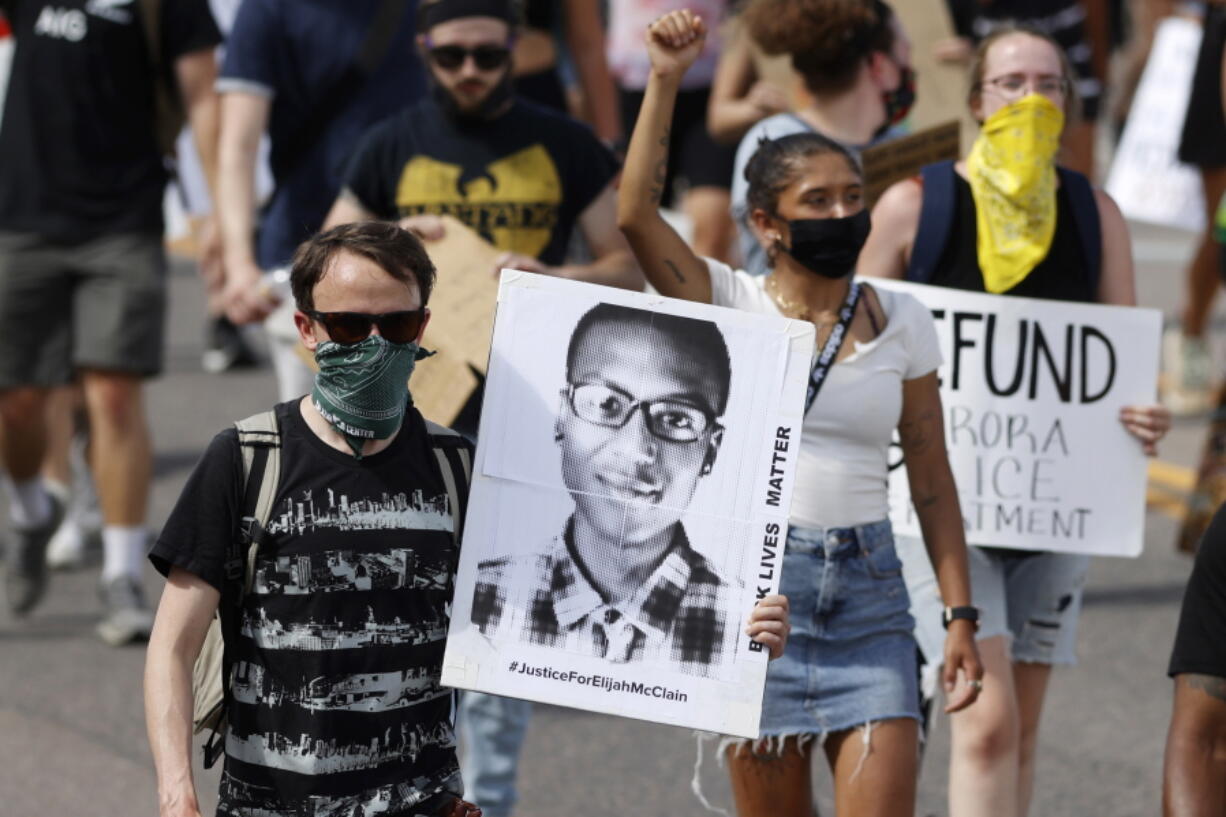 FILE - A demonstrator carries an image of Elijah McClain during a rally and march in Aurora, Colo., June 27, 2020. A Colorado judge on Friday, Sept. 16, 2022 responded to a request by a coalition of news organizations to release an amended autopsy report for Elijah McClain, a 23-year-old Black man who died after a 2019 encounter with police, by ruling the report be made public only after new information it contains is redacted.