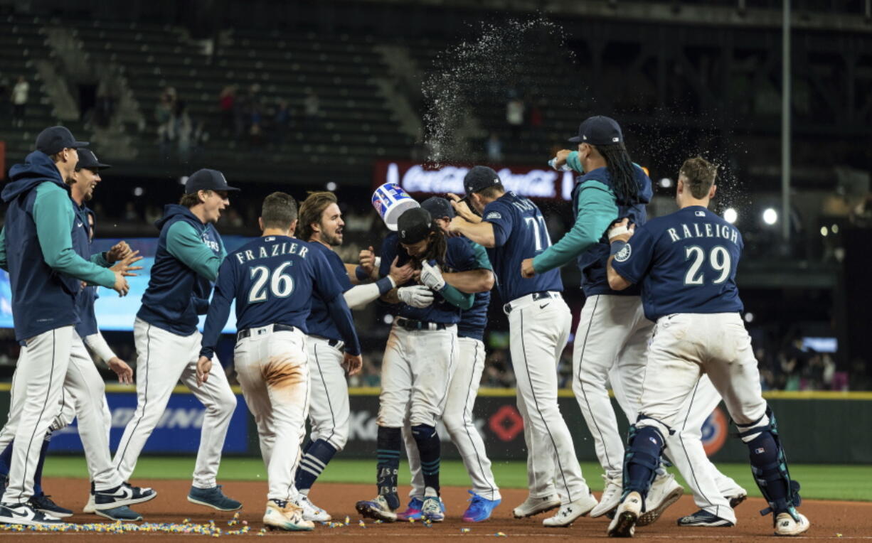 Seattle Mariners, including Adam Frazier (26), J.P. Crawford, center, Chris Flexen (77), Luis Castillo, second from right, and Cal Raleigh, right, celebrate after a single by Crawford in the 11th inning drove in the winning run in a baseball game against the Texas Rangers, Thursday, Sept. 29, 2022, in Seattle. The Mariners won 10-9.