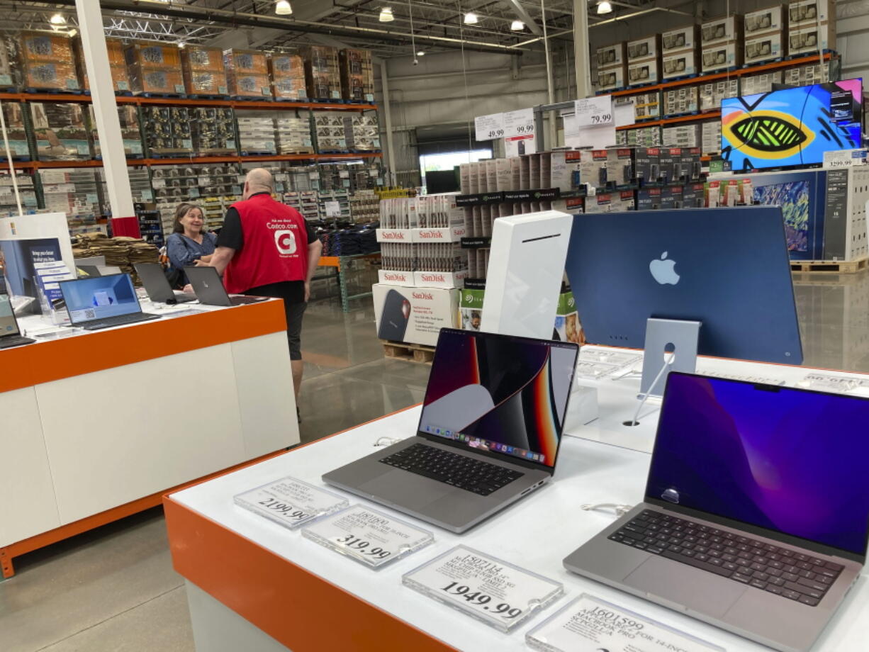 A sales associate helps a prospective customer as laptops sit on display in a Costco warehouse, Aug. 15, 2022, in Sheridn, Colo. Americans picked up their spending a bit in August from July even as surging inflation on household necessities like rent and food take a toll on household budgets. The U.S. retail sales rose an unexpected 0.3 percent last month, from being down 0.4 percent in July,  the Commerce Department said Thursday., Sept. 15, 2022.