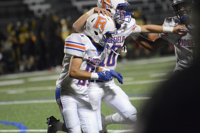Ridgefield’s Cash Hill runs off the field with quarterback Logan DeBeaumont after scoring a touchdown in the fourth quarter a 2A Greater St. Helens League football game at Kiggins Bowl on Thursday, Sept. 22, 2022.