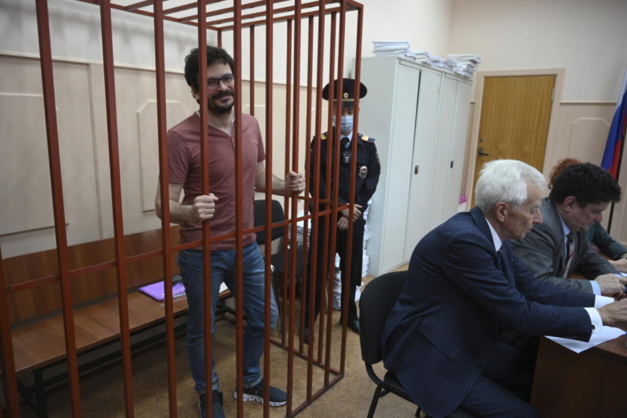 Russian opposition activist and municipal deputy of the Krasnoselsky district Ilya Yashin stands behind bars in a cage during a hearing on his detention, at the Basmanny district court in Moscow, Russia, Friday, Sept. 9, 2022. Yashin, 39, is one of the few prominent opposition figures that refused to leave Russia despite the unprecedented pressure the authorities have mounted on dissent in recent years.