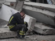 A rescue worker takes a pause as he sits on the debris at the scene where a woman was found dead after a Russian attack that heavily damaged a school in Mykolaivka, Ukraine, Wednesday, Sept. 28, 2022.