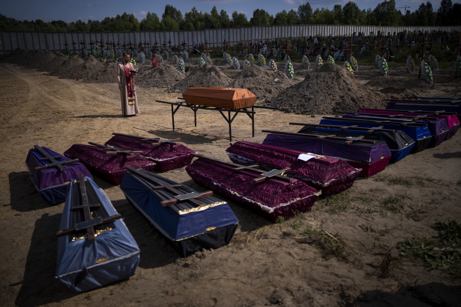 A priest blesses coffins with unidentified civilian bodies, who died on the territory of the Bucha community during the Russian occupation period in February-March 2022, during a funeral in Bucha, near Kyiv, Ukraine, on Friday, Sept. 2, 2022.