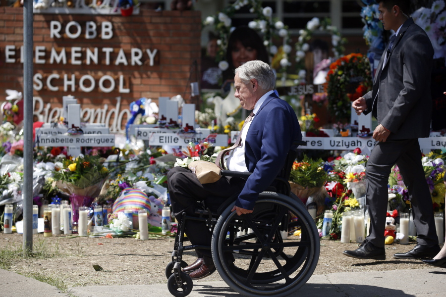 FILE - Texas Gov. Greg Abbott passes in front of a memorial outside Robb Elementary School to honor the victims killed in a school shooting in Uvalde, Texas, May 29, 2022.  In the aftermath of the school shooting in Uvalde, Texas, governors around the country vowed to take steps to ensure their students would be kept safe. Months later, as students return to classrooms, money has begun to flow for school security upgrades, training and other new efforts to make classrooms safer.