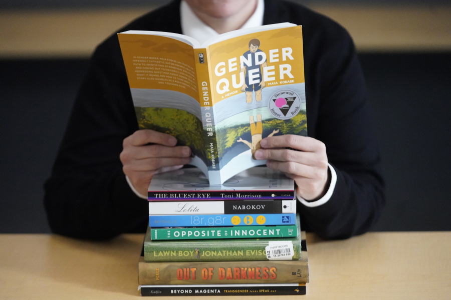 Amanda Darrow, director of youth, family and education programs at the Utah Pride Center, poses with books that have been the subject of complaints from parents in Salt Lake City on Dec. 16, 2021.