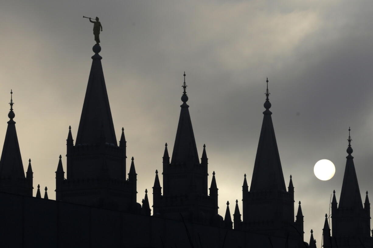 FILE - The angel Moroni statue atop the Salt Lake Temple is silhouetted against a cloud-covered sky, at Temple Square in Salt Lake City on Feb. 6, 2013.