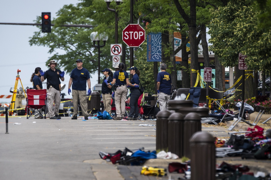 FILE - Members of the FBI Evidence Response Team Unit investigate in downtown Highland Park, Ill., on July 5, 2022, the day after a deadly mass shooting at a Fourth of July Parade. According to a lawsuit filed Wednesday, Sept. 28, 2022, in Illinois, the gunmaker Smith & Wesson illegally targeted young men at risk of violence with ads for firearms, including the 22-year-old gunman accused of opening fire on the Independence Day parade in suburban Chicago and killing seven people.