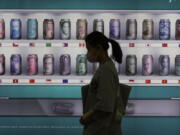 A woman walks by a bank's currency advertisement board in Seoul, South Korea, Friday, Sept. 23, 2022. Asian stocks fell for a third day Friday after more rate hikes by the Federal Reserve and other central banks to control persistent inflation spurred fears of a possible global recession.