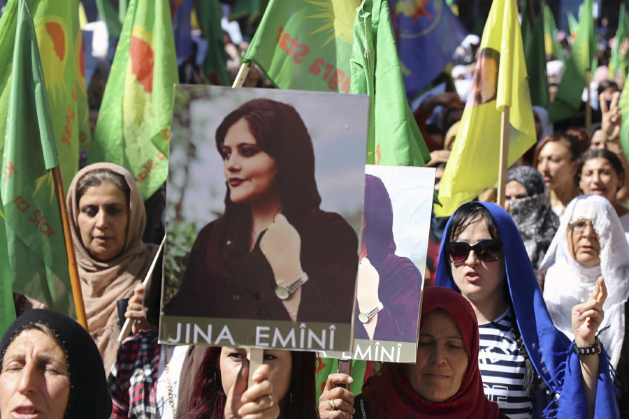 In this photo provided by Kurdish-run Hawar News Agency, Kurdish women hold portraits of Iranian Mahsa Amini, during a protest condemning her death in Iran, in the city of Qamishli, northern Syria, Monday, Sept. 26, 2022. Protests have erupted across Iran in recent days after Amini, a 22-year-old woman, died while being held by the Iranian morality police for violating the country's strictly enforced Islamic dress code.