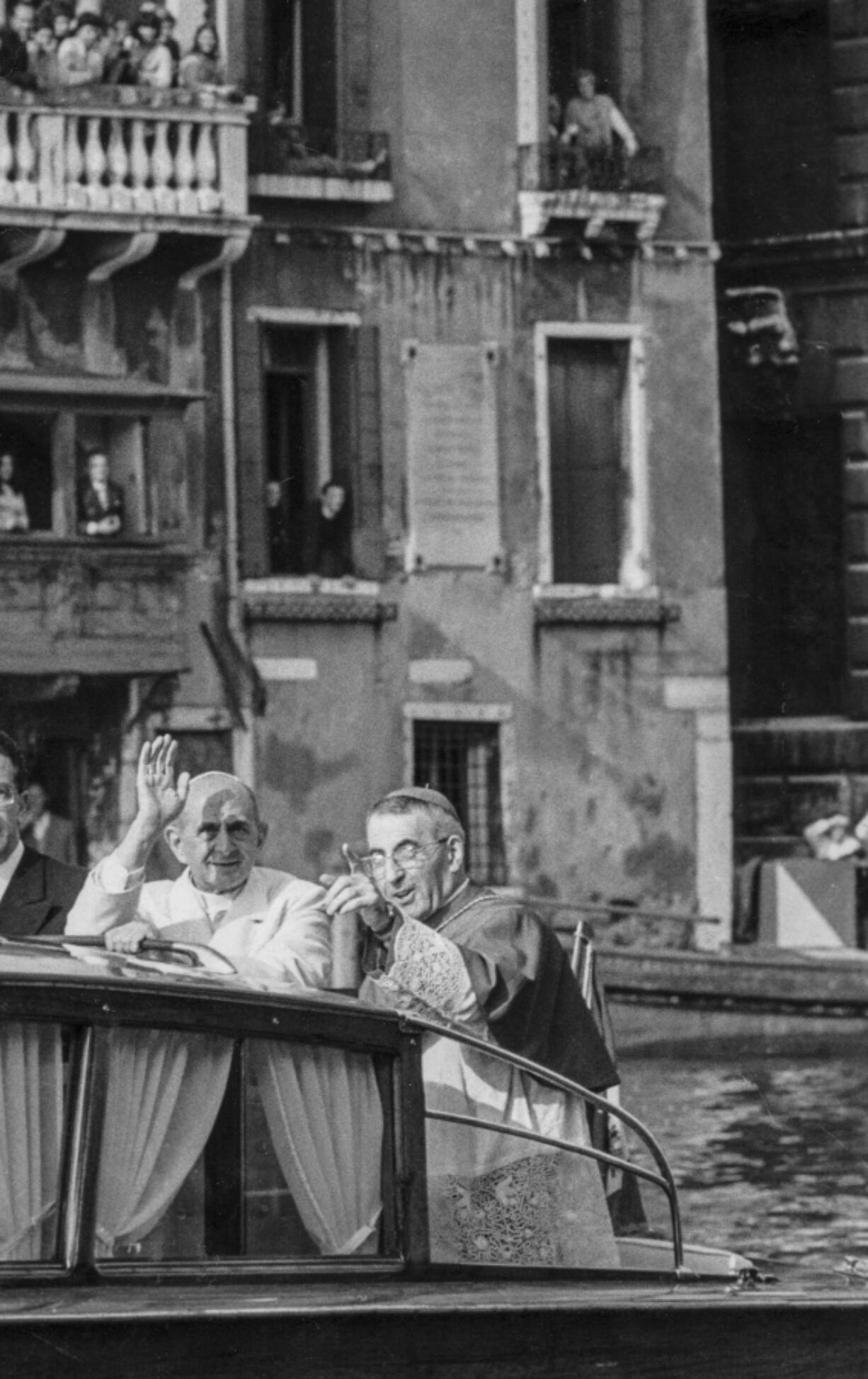 FILE - Pope Paul VI, left, waves to the crowd while Venice Patriarch Cardinal Albino Luciani points to a landmark as they ride in a motorboat in Venice, northern Italy. On Sunday, Sept. 4, 2022, Pope Francis will beatify John Paul I, the last formal step before on the path to possible sainthood.