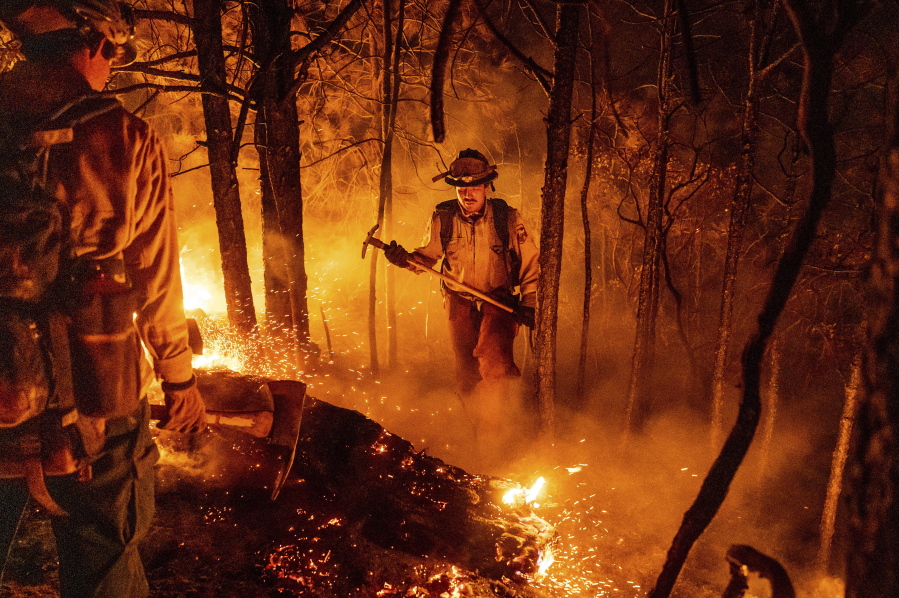 Firefighter Christian Mendoza manages a backfire, flames lit by firefighters to burn off vegetation, while battling the Mosquito Fire in Placer County, Calif., on Tuesday, Sept. 13, 2022.