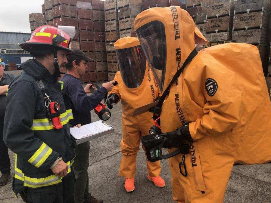 Two members of Vancouver's Hazardous Materials Team, right, get supplies before entering Northwest Packing Co. at the Port of Vancouver to respond to a toxic chemical mixture Tuesday morning. Twelve employees were evaluated by medical personnel after possibly inhaling the mixture.