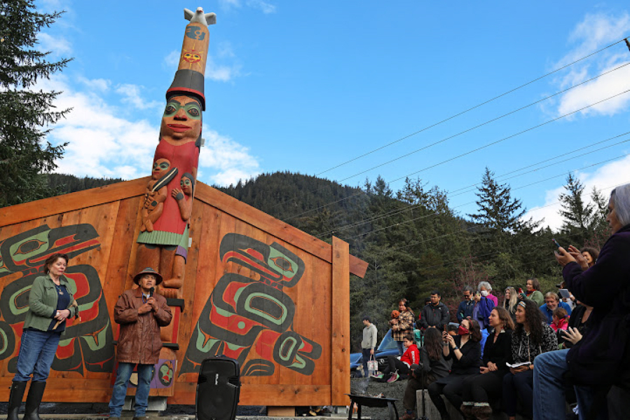 Tlingit master carver Wayne Price stands next to his wife in front of the healing totem pole and screens he created. Hundreds of people gathered in raincoats and boots at the Twin Lakes Kaasei Totem Plaza to witness the two-hour ceremony.