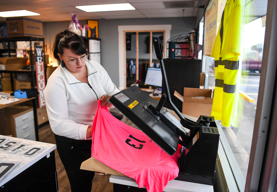 Screen printing is the process of transferring stenciled designs onto fabric. In this case, Krystin Alexander uses a large iron to adhere the design to this T-shirt.
